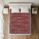 Kola Abstract Print Cotton Throw Blanket in Red, on a bed
