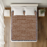 Kola Abstract Print Cotton Throw Blanket in Rust Brown, on a bed