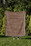 Kola Abstract Print Cotton Throw Blanket in Rust Brown, outdoors