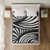 Konga Hand Woven Throw Blanket in Black, on a bed