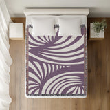 Konga Hand Woven Throw Blanket in Purple, on a bed