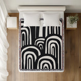 Lyno Abstract Print Cotton Throw Blanket in Black, on a bed