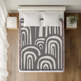 Lyno Abstract Print Cotton Throw Blanket in Gray, on a bed