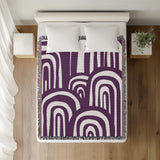 Lyno Abstract Print Cotton Throw Blanket in Purple, on a bed