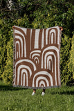 Lyno Abstract Print Cotton Throw Blanket in Rust Brown, outdoors