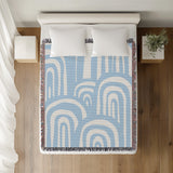Lyno Abstract Print Cotton Throw Blanket in Sky, on a bed