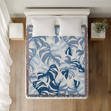 Monstera Leaf Cotton Throw Blanket in Blue, on a bed