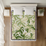 Monstera Leaf Cotton Throw Blanket in Green, on a bed