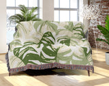 Monstera Leaf Cotton Throw Blanket in Green, draped over a sofa