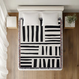 Pereto Abstract Print Cotton Throw Blanket in Black, on a bed