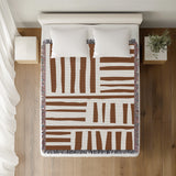 Pereto Abstract Print Cotton Throw Blanket in Rust Brown, on a bed
