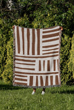 Pereto Abstract Print Cotton Throw Blanket in Rust Brown, outdoors