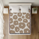 Poppi Floral Cotton Throw Blanket in Beige, on a bed