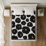 Poppi Floral Cotton Throw Blanket in Black, on a bed