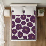Poppi Floral Cotton Throw Blanket in Purple, on a bed