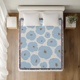 Poppi Floral Cotton Throw Blanket in Sky, on a bed