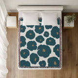 Poppi Floral Cotton Throw Blanket in Teal, on a bed