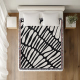 Pyro Abstract Print Cotton Throw Blanket in Black, on a bed