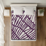 Pyro Abstract Print Cotton Throw Blanket in Purple, on a bed