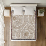 Ray Abstract Print Cotton Throw Blanket in Beige, on a bed