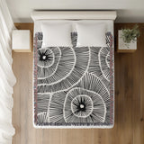 Ray Abstract Print Cotton Throw Blanket in Black, on a bed