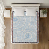 Ray Abstract Print Cotton Throw Blanket in Sky, on a bed