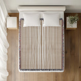 River Striped Cotton Throw Blanket in Beige, on a bed