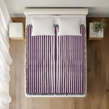 River Striped Cotton Throw Blanket in Purple, on a bed