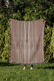 River Striped Cotton Throw Blanket in Rust Brown, outdoors