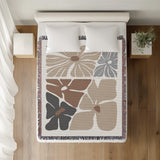 Roni Floral Cotton Throw Blanket in Beige, on a bed