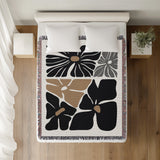 Roni Floral Cotton Throw Blanket in Black, on a bed