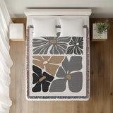 Roni Floral Cotton Throw Blanket in Gray, on a bed