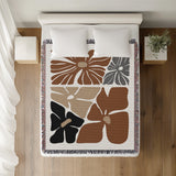 Roni Floral Cotton Throw Blanket in Rust Brown, on a bed