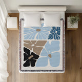 Roni Floral Cotton Throw Blanket in Sky, on a bed