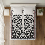 Sani Cheetah Print Cotton Throw Blanket in Black and Off-White, on a bed