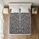 Sani Cheetah Print Cotton Throw Blanket in Gray, on a bed
