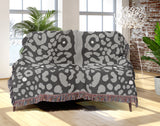 Sani Cheetah Print Cotton Throw Blanket in Gray, draped over a sofa