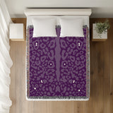 Sani Cheetah Print Cotton Throw Blanket in Purple, on a bed