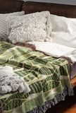 Sansevieria Leaf Cotton Throw Blanket in Green, on a bed