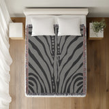 Sasha Zebra Print Cotton Throw Blanket in Gray, on a bed