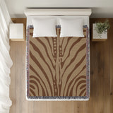 Sasha Zebra Print Cotton Throw Blanket in Rust Brown and Beige, on a bed