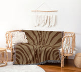 Sasha Zebra Print Cotton Throw Blanket in Rust Brown and Beige, draped over a sofa