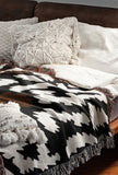 Sassi Animal Print Cotton Throw Blanket in Black, Rust Brown and Beige, draped over a sofa