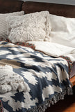 Sassi Animal Print Cotton Throw Blanket in Gray, Beige and Blue, draped over a sofa