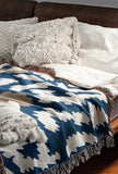 Sassi Animal Print Cotton Throw Blanket in Navy Blue, Beige and Blue, draped over a sofa