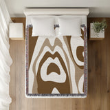 Shai Animal Print Cotton Throw Blanket in Beige and Brown, on a bed