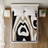 Shai Animal Print Cotton Throw Blanket in Black and Beige, on a bed
