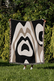 Shai Animal Print Cotton Throw Blanket in Black and Beige, draped over a sofa