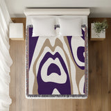 Shai Animal Print Cotton Throw Blanket in Lilac and Beige, on a bed