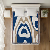 Shai Animal Print Cotton Throw Blanket in Navy Blue and Beige, on a bed
